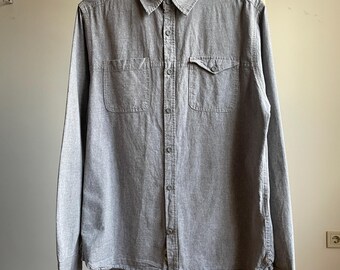 May include: A gray long-sleeved button-down shirt with two chest pockets.