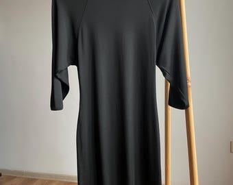 May include: Black short-sleeved dress with a round neckline and raglan sleeves. The dress is hanging on a wooden hanger.
