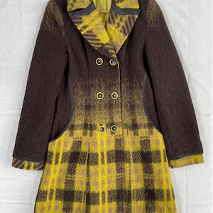 May include: A double-breasted coat featuring a dark brown upper section and a vibrant yellow and brown plaid lower section. The coat has a wide collar, long sleeves with dark brown cuffs, and six circular buttons down the front center.