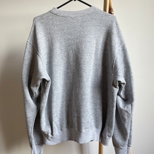 May include: A heather grey sweatshirt with a crew neck.