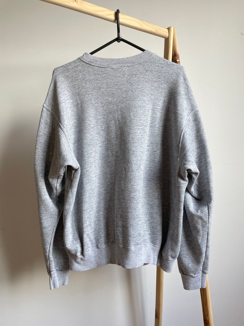 May include: A heather grey sweatshirt with a crew neck.