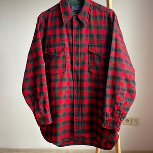 Pode incluir: Camisa de flanela xadrez vermelha e verde com colarinho de botões e dois bolsos no peito.