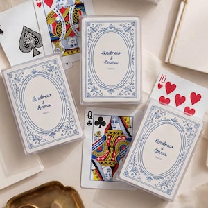 May include: Three clear plastic cases containing custom playing cards with a blue oval frame and the text Andrew & Emma printed on the front. The cards are displayed alongside standard playing cards including an ace, king, queen, and ten of hearts.