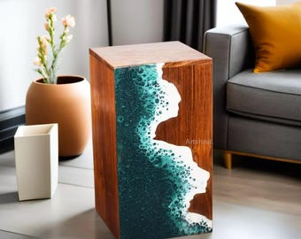 May include: A wooden side table with a teal and white resin wave design. The table is made of dark wood and has a square top.