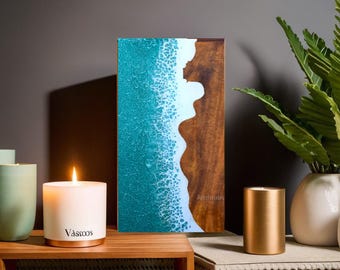 May include: A teal and white resin art piece with a wood frame. The resin is shaped like a wave crashing on a shore. The piece is titled "Artstudio".