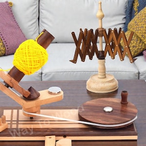 Puede incluir: Juego de devanadera y ovilladora de hilo de madera. La devanadera de hilo tiene un diseño en acordeón marrón oscuro. La ovilladora tiene una base de madera con una parte superior circular marrón oscuro. Una madeja de hilo amarillo está en la ovilladora.