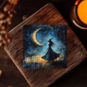 May include: Square artwork depicting a witch in a long black dress and hat, set against a crescent moon. The background is a dark blue night sky with gold accents and stars. The artwork is on a wooden surface.