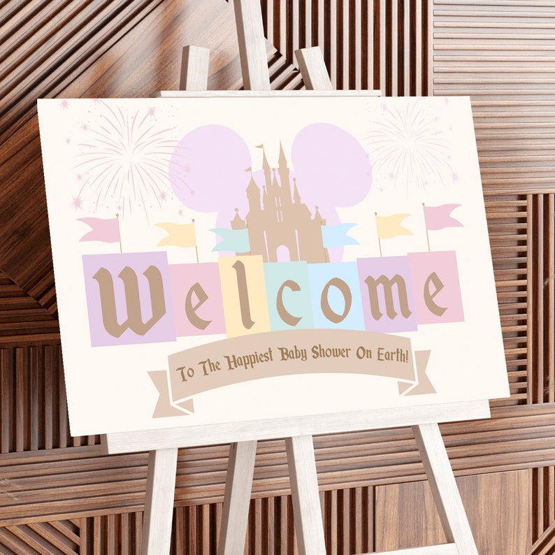 May include: A welcome sign for a baby shower with a pastel pink, blue, and yellow color scheme. The sign features a silhouette of Cinderella's castle with fireworks and the text "Welcome to the Happiest Baby Shower on Earth!"