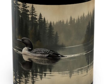 May include: Black coffee mug with a scenic image of a loon swimming in a lake with a forest in the background.