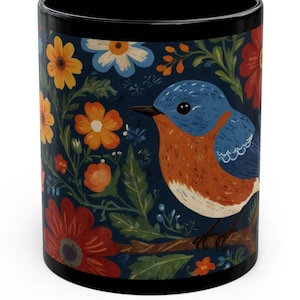 May include: A black ceramic mug with a colorful floral pattern and a bluebird perched on a branch. The flowers are red, orange, yellow, and white.