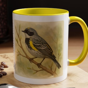 May include: A white ceramic mug with a yellow rim and handle. The mug features a watercolor illustration of a yellow-rumped warbler perched on a branch.