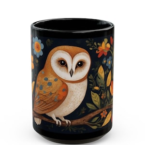 May include: A black ceramic mug with a white barn owl perched on a branch with colorful flowers and leaves. The owl has brown and orange feathers and large yellow eyes.