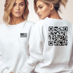 May include: Two white sweatshirts with black designs. One sweatshirt has a black American flag on the front. The other sweatshirt has a black QR code on the back.