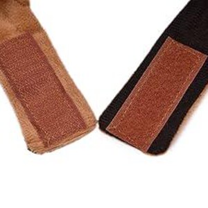 May include: Close-up of two brown faux fur straps with brown hook and loop fasteners. The straps are attached to a black fabric.