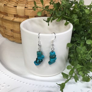 May include: Turquoise gemstone dangle earrings with silver hooks. The turquoise stones are stacked and have a rough, natural look.