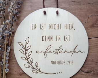 May include: A round wooden sign with the text "Er ist nicht hier, denn er ist auferstanden. Matthäus 28,6" and a floral design.