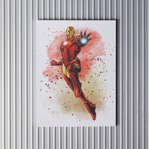 Puede incluir: Una pintura de acuarela de Iron Man volando por el aire con un traje rojo y dorado. El fondo es una acuarela roja y amarilla.