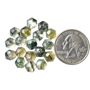 May include: A collection of faceted, hexagonal moss agate beads in shades of green, white, and gray. A U.S. quarter is included for size comparison, showcasing the beads' small size. The beads have a natural, earthy appearance.