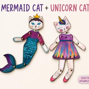 以下が含まれることがあります： MERMAID CAT + UNICORN CATおよびDIGITAL DOWNLOADというテキストが書かれた、2体の関節付き紙製猫フィギュア。マーメイド猫は青い尾と金の冠を身につけ、ユニコーン猫はカラフルな角、虹色のドレス、ピンクのバレエシューズを身につけている。