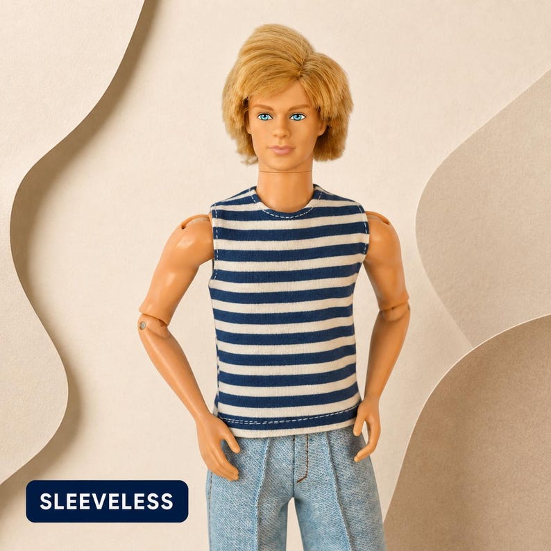 Puede incluir: Una mu&ntilde;eca con cabello rubio viste una camiseta sin mangas con rayas horizontales azul marino y blancas combinada con pantalones de mezclilla azul claro. La mu&ntilde;eca tiene ojos azules y expresi&oacute;n neutra. Una etiqueta azul oscuro muestra el texto SLEEVELESS.