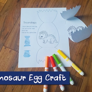May include: A printable dinosaur egg craft template featuring a Triceratops dinosaur. The template includes instructions to colour the dinosaur and egg, cut out on the solid black line, and fold on the dotted line. The image also shows a finished craft with a grey egg and a dinosaur peeking out.