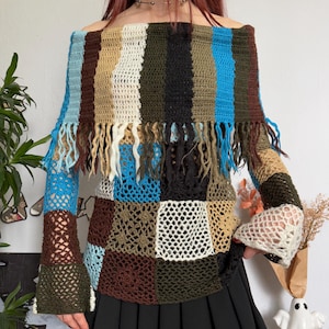Puede incluir: Top de crochet multicolor, con hombros descubiertos, mangas largas y flecos. El top presenta un diseño de patchwork con varios colores, incluyendo azul, marrón, beige y verde. Las mangas son acampanadas.