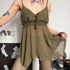K&ouml;nnte beinhalten: Olivgr&uuml;nes Camisole-Top mit Spaghettitr&auml;gern und geraffter Empire-Taille. Der transparente Stoff f&auml;llt locker und erzeugt eine flie&szlig;ende Silhouette. Das Top hat eine zarte Spitzenborte am Ausschnitt.