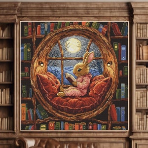 Pode incluir: Um bordado de ponto cruz que representa um coelho sentado em uma cadeira redonda, lendo um livro em frente a uma janela. O coelho está vestindo um camisão rosa e a cadeira está cercada por estantes cheias de livros.