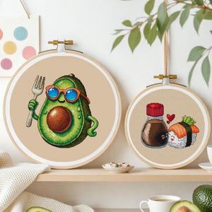 Peut inclure: Deux cercles de broderie avec des motifs sur le thème de la nourriture. L'un représente un avocat portant des lunettes de soleil et tenant une fourchette. L'autre montre une bouteille de sauce soja et des sushis avec un cœur.