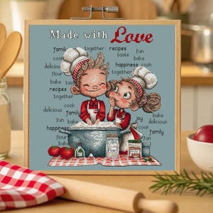 May include: A framed artwork featuring a cartoon illustration of two chefs, a boy and a girl, cooking together. The artwork includes the text "Made with Love" and other cooking-related words. The color palette includes red, white, and blue.