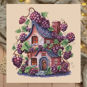 Pode incluir: Um padrão de ponto cruz de uma pequena casa de tijolo com um telhado roxo e uma videira de uvas crescendo ao redor. A casa tem uma porta e duas janelas. As uvas são roxas e verdes.