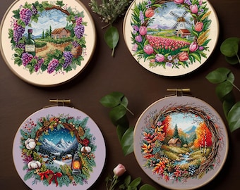 May include: Four embroidery hoop designs featuring floral wreaths with different scenes inside. The top left hoop shows a vineyard with a bottle of wine. The top right hoop shows a windmill and a house. The bottom left hoop shows a winter scene with a lantern. The bottom right hoop shows a forest scene with a stream.
