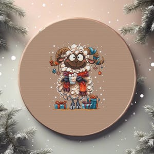Pode incluir: Um desenho de ponto cruz de uma ovelha usando um cachecol vermelho e segurando uma xícara, cercada por presentes. A ovelha tem chifres marrons e é decorada com ornamentos. O desenho está em um bastidor de bordado redondo e bege.