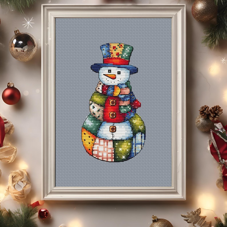 Pode incluir: Imagem de ponto cruz emoldurada de um boneco de neve. O boneco de neve tem um design de retalhos com cartola, cachecol e bot&otilde;es. A paleta de cores inclui azul, vermelho, verde e amarelo. Decora&ccedil;&otilde;es de Natal no fundo.