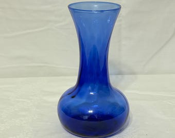 Op de afbeelding: Een kobaltblauwe glazen vaas met een afgeronde basis en een uitlopende bovenkant. De vaas heeft een gladde, glanzende afwerking en een kleurverloop, van een lichter blauw aan de bovenkant naar een dieper blauw aan de basis. De vaas is leeg.