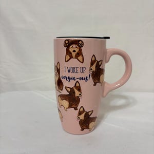 May include: A white ceramic mug with a black handle and the text "But First, Coffee" in a bold, black font. The mug is set against a blurred background, suggesting a cozy setting.