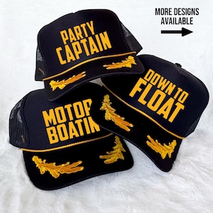 May include: Three black mesh trucker hats with gold embroidery. The hats have the following text: "Party Captain", "Motor Boatin", and "Down to Float".