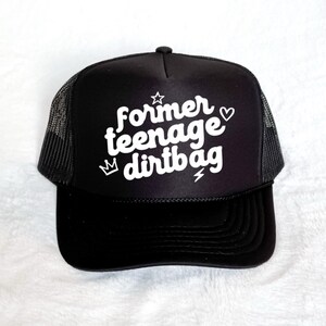 Può includere: Cappellino da camionista nero con visiera curva e retro in rete. Il cappellino presenta il testo bianco "former teenage dirtbag" con una stella, un cuore, una corona e un fulmine.