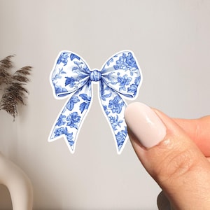 May include: A blue and white floral patterned bow. The bow is made of a white fabric with a blue floral pattern.