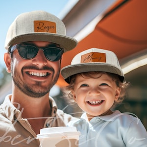 May include: A father and son wearing matching gray and white baseball caps with brown leather patches. The father's cap says "Roger" and the son's cap says "Marcus".