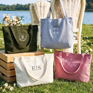 Może przedstawiać: Cztery torby typu tote z sztruksu w kolorach oliwkowym, jasnoniebieskim, kremowym i brudnego różu. Każda torba ma dwa paski na ramię i personalizowany haft: zielona ma literę R w wieńcu, niebieska napis Helen, kremowa E|S, a różowa napis Rosie.
