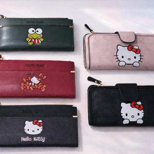 Pode incluir: Uma variedade de carteiras retangulares em várias cores, incluindo verde, bordô, preto e rosa. Cada carteira apresenta um personagem de desenho animado diferente, como Hello Kitty e Keroppi. As carteiras têm fecho de correr e uma alça de pulso.