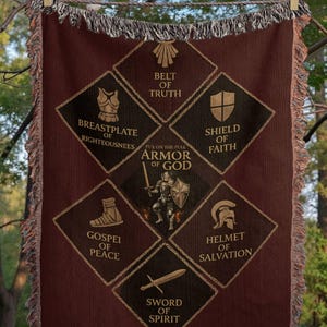 May include: A burgundy throw blanket with a fringed edge, featuring a design of the Armor of God. The design includes a breastplate, shield, helmet, sword, and other symbols, with text that reads "Armor of God". The blanket is personalized with the name "Michael".