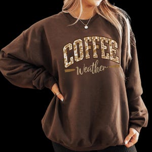 May include: Brown sweatshirt with a brown and white leopard print graphic that says "Coffee Weather".