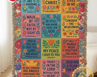 May include: A colorful woven throw blanket featuring inspirational Bible verses in a patchwork design. The blanket has a floral border and includes phrases like "Angels are guarding you" and "All things through Christ."
