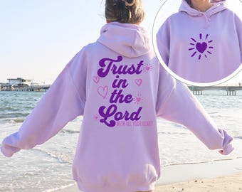 May include: A lavender hoodie with a purple graphic on the back that says "Trust in the Lord with all your heart". The graphic includes hearts and suns. The front of the hoodie has a purple sun with a heart in the center.