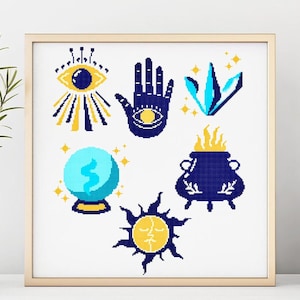 Puede incluir: Una impresión enmarcada con seis símbolos místicos en estilo punto de cruz. Los símbolos incluyen un ojo, una mano con un ojo, un cristal, una bola de cristal, un caldero con llamas y un sol con una cara. La paleta de colores es azul marino, amarillo y turquesa.