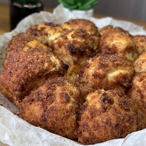 May include: A close-up shot of a basket filled with freshly baked cinnamon rolls. The rolls are golden brown with a generous coating of cinnamon sugar. The rolls are arranged in a white paper-lined basket, ready to be enjoyed.