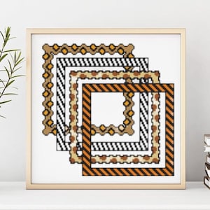 May include: A framed cross-stitch artwork featuring four nested square frames. The frames have various patterns, including stripes, dots, and a dotted border, in shades of brown, black, and orange. The artwork is displayed on a white surface.