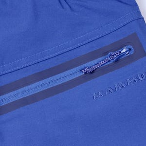 Puede incluir: Primer plano de tela azul con un bolsillo con cremallera. La cremallera es azul con un borde azul oscuro. La palabra "MAMMUT" est&aacute; bordada en azul oscuro en la tela.